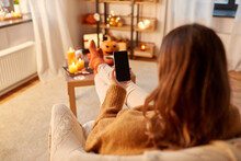 Halloween, Holidays And Leisure Concept - Young Woman Using Smartphone At Home