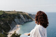 © Eva - close up of relaxed woman sitting on top of the cliff looking at sea landscape in Asturias. Relax and nature concept