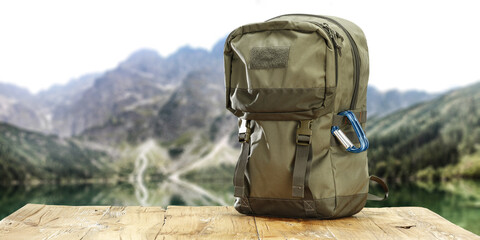 green backpack on wooden desk and free space for your decoration