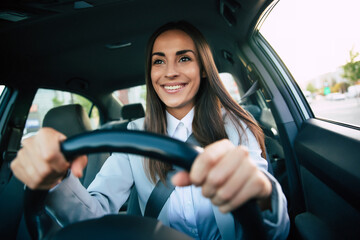 Portrait of cute female driver steering car with safety belt