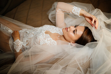 a gentle bride in a lace robe lies in bed on a veil. morning before the wedding.