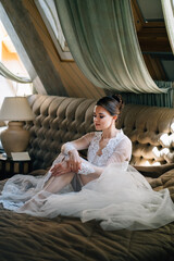 Wall Mural - a bride in a lace robe sitting in bed. morning before the wedding.