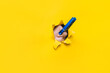 A blue clothespin on the girl's nose. Torn hole in yellow paper. The concept of a runny nose, combating stench, loss of smell in the coronavirus covid-19.