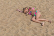 portrait of a child on the seashore, top view, sad girl 7 years old, blonde, lies on the beach on the sand, on her side.