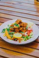 Canvas Print - Vertical shot of a salad with nuggets on a white plate on wooden table