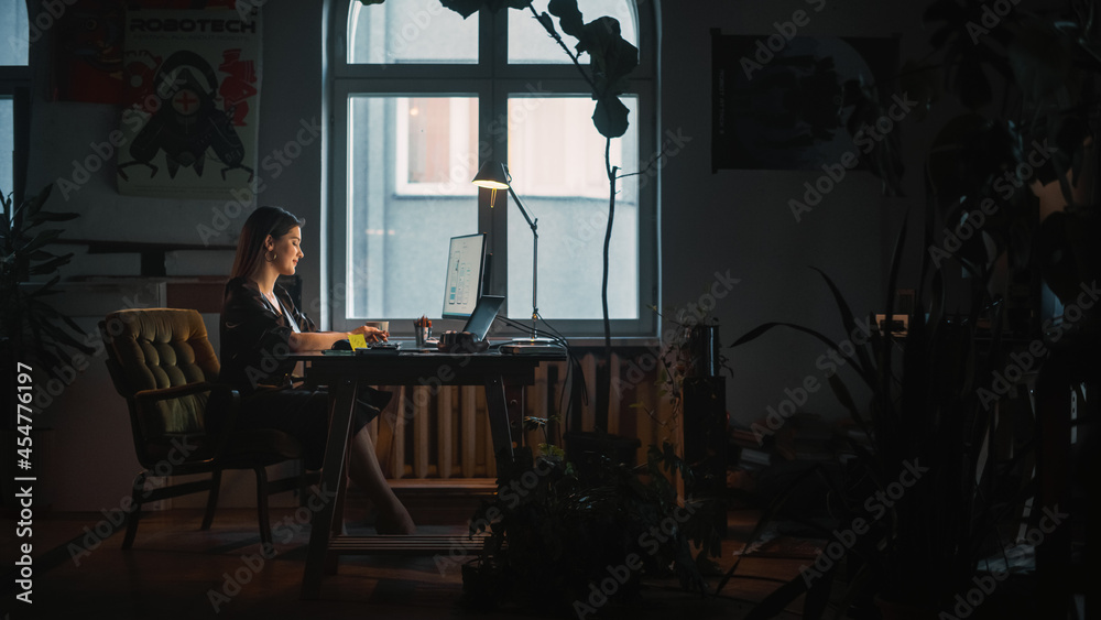 Young Female Professional Works on a Desktop Computer in Creative Agency in Authentic Loft Office. Renovated Stylish Design with House Plants, Artistic Posters and Big Windows. Dark Room. - obrazy, fototapety, plakaty 