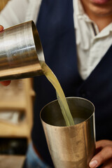 Long drink, sweet yellow transparent and white drink with pineapple decoration. Preparation of a drink with white drink, alcohol, liquor. Bartender's hands.