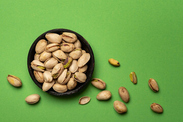 Roasted pistachiosin a bowl on green background