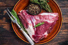Raw Lamb Mutton Thigh Or Leg With Rosemary And Thyme In Rustic Plate. Dark Wooden Background. Top View