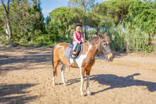 Little Girl Riding On A Stopped Horse In The Countryside
