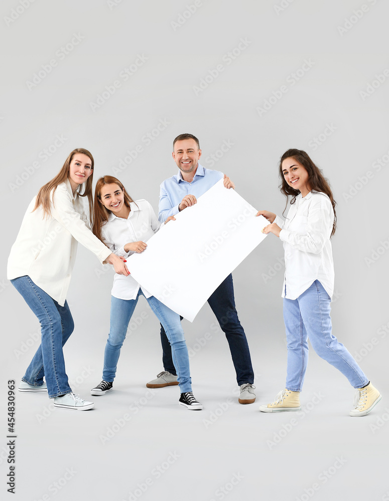 Group of people with blank poster on light background