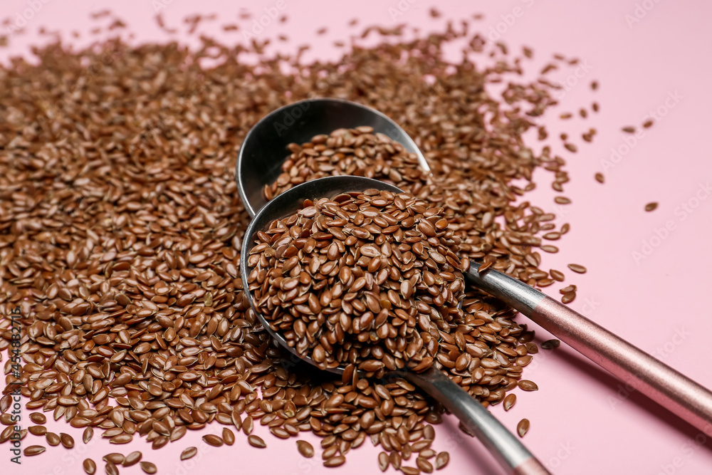 Spoons with flax seeds on color background, closeup