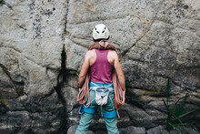 Young Woman Wearing In Climbing Equipment Standing In Front Of A Stone Rock Outdoor And Preparing To Climb