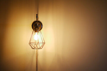 Canvas Print - Closeup shot o a light bulb in a modern lamp in front of a plain wall