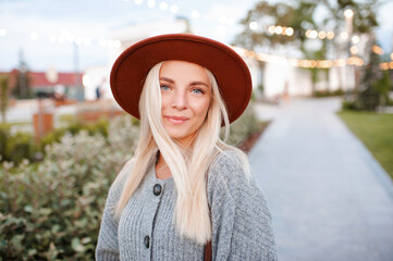 beautiful blonde smiling adult girl 20-24 year old wear casual warm clothes and hat posing in city p