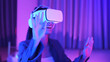 Young asian woman is using virtual reality headset. Neon light studio portrait. Concept of virtual reality, simulation, gaming and future technology.Asian woman play game in bedroom.