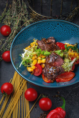 Wall Mural - Steak salad with vegetables, corn, roasted peppers, cherry tomatoes and soy sauce on a dark stone table