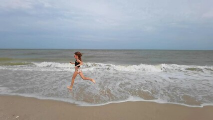 Wall Mural - Little kid girl plays on beach shallow water line summer rest during vacations