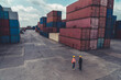 © InfiniteFlow - Industrial worker works with co-worker at overseas shipping container yard . Logistics supply chain management and international goods export concept .