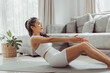© sarayutsridee - Young woman exercising at home. Asian healthy woman in sportwear doing abs and core exercise at home. Home workout.