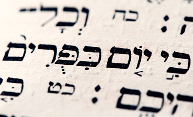 Poster - Closeup of hebrew words Yom Kippur in Torah page that translate in english as Day of Atonement, holiest day of the year in Judaism. Selective focus.