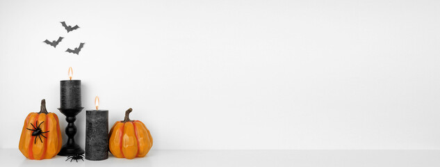 Poster - Halloween shelf display with pumpkins, black candles and spiders against a white wall with bats. White shelf. Banner with copy space.