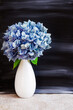 © Karynf - Hydrangea flowers in a vase against a black painted background; Simple arrangement of bouquet against a dark background