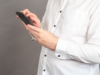 Poster - hands of man with phone. businessman in shirt holds cellphone. male dials number into cellphone. man