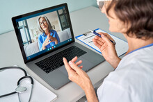 Female Doctor Therapist Consulting Older Senior Patient Via Virtual Video Call Visit Using Laptop Computer. Digital Online Healthcare, Distance Telemedicine. Telehealth Videocall. Over Shoulder View