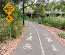 'Caution Blind Spot Ahead' - Warning signs and road markings along a shared bicycle and pedestrian pathway