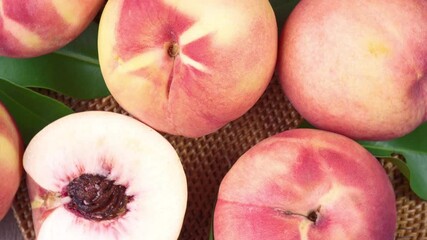 Wall Mural - top view rotate fresh peach with slices closeup, white peach on bamboo mat on wooden table in garden