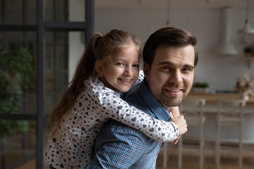 Sticker - Portrait happy millennial best dad piggybacking daughter kid at home. Father carrying cute girl on his back, looking at camera, smiling, having fun with child. Parenthood, active family concept