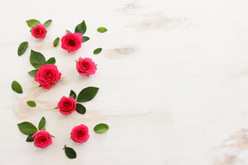 Wall Mural - White wooden delicate background with pink roses and petals. Top view