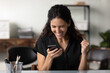 Happy millennial Latin woman in casual excited with good news, using smartphone, looking at screen, making winner yes gesture. Businesswoman reading text message, celebrating win, high result