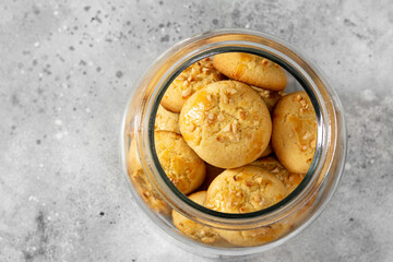 Wall Mural - Homemade Norwegian butter cookies with almonds in a glass jar on a light gray culinary background. Traditional Scandinavian pastries top view