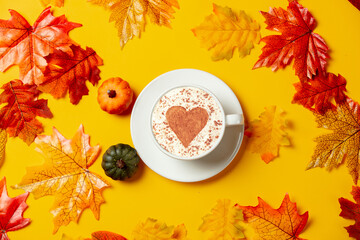 Wall Mural - Romantic cup of coffee and little pumpkins with autumn leaves on yellow background. Top view