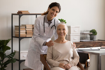 Wall Mural - Portrait of happy senior lady visiting doctor, looking at camera, smiling, keeping good health due to checkup, geriatric medic care. Head shot of optimistic female practitioner and elderly patient