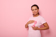 © Taras Grebinets - African American woman puts hands around pink ribbon on her pink T Shirt, for breast cancer campaign, supporting Breast Cancer Awareness. Concept of 1 st October Pink Month and women's health care