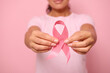 © Taras Grebinets - Cropped view of young woman in pink t-shirt holding a pink satin ribbon isolated on colored background with copy space. International Breast Cancer awareness Day, Breast cancer support concept.