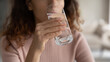 © fizkes - Close up young woman drinking glass of fresh pure water, improving metabolism, preventing dehydration, enjoying morning habit, sipping distilled aqua, feeling thirsty indoors, detoxing organism.