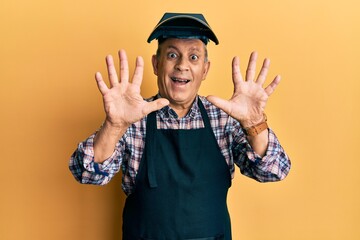 Poster - Handsome senior man with grey hair wearing welding protection mask showing and pointing up with fingers number ten while smiling confident and happy.