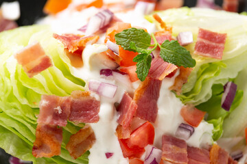 Iceberg wedge salad with bacon, cherry tomatoes, red onion and dressing. healthy food