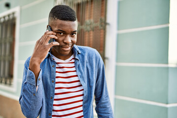 Young african american man smiling happy talking on the smartphone at the city.