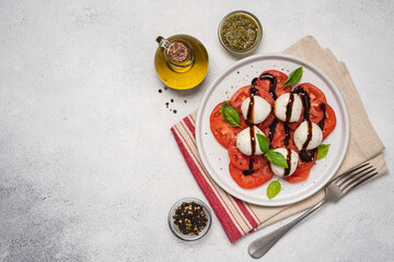 Wall Mural - Caprese salad with tomatoes, basil, mozzarella, balsamic sauce and olive oil. Traditional Italian food. Top view, white background, copy space