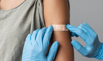 doctor putting plaster at female hand after injection of a corona virus vaccine closeup. corona viru