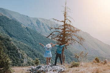 Loving couple are romantically posing against the background of the mountains. Man and woman posing on a sunny day in the mountains.