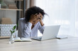 Professional burnout. Depressed upset mixed race female sit at workplace by computer hug head feel unmotivated sick lack of sleep. Desperate young black woman having problems at work missed deadline