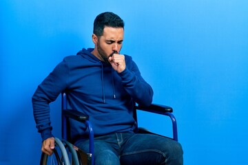 Wall Mural - Handsome hispanic man with beard sitting on wheelchair feeling unwell and coughing as symptom for cold or bronchitis. health care concept.