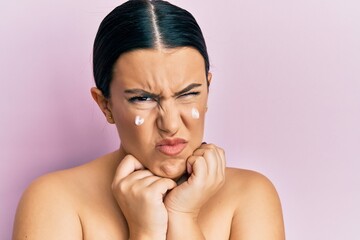 Poster - Beautiful brunette woman standing topless wearing face cream skeptic and nervous, frowning upset because of problem. negative person.