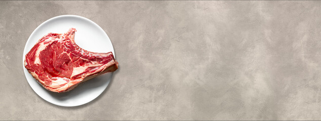 Wall Mural - Beef prime rib and plate isolated on light concrete background. Horizontal banner